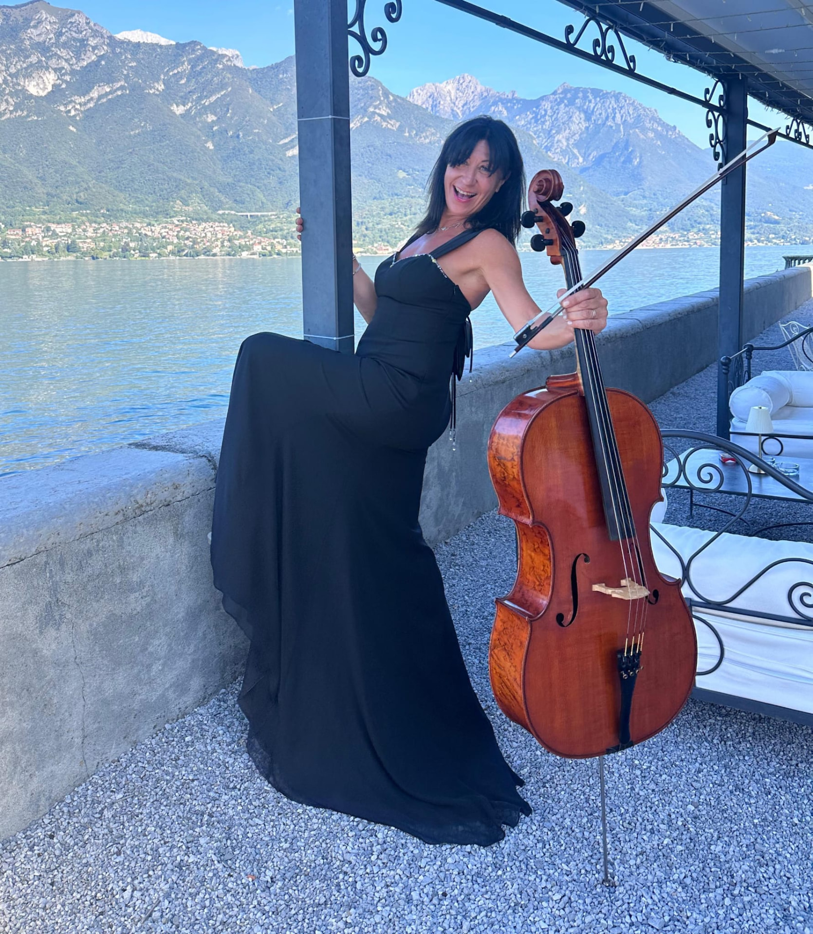 Ilaria Giorgi in abito nero con il violoncello a bordo lago per un evento luxury